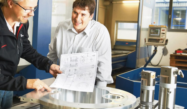Machinists happily reviewing their machined part.